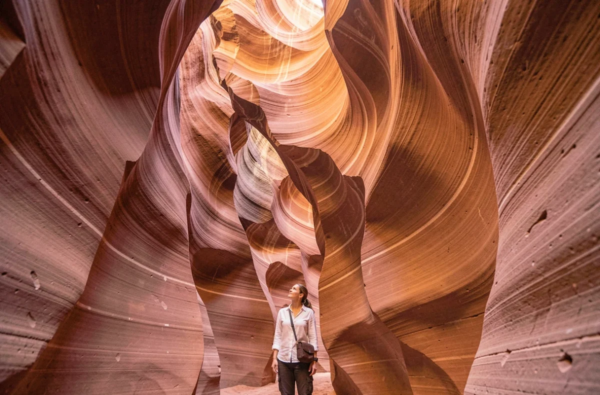 Voyageuse explorant les parois sinueuses de l'Antelope Canyon en Arizona, l'un des paysages les plus spectaculaires des États-Unis