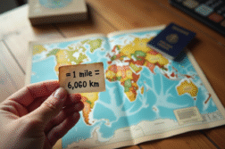 Main d'un voyageur tenant un papier avec miles et km